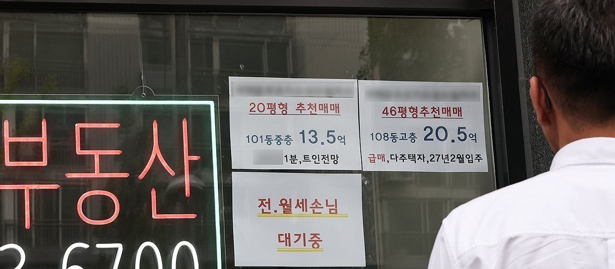 중개업소 유리창의 매물 전단을 보는 사람