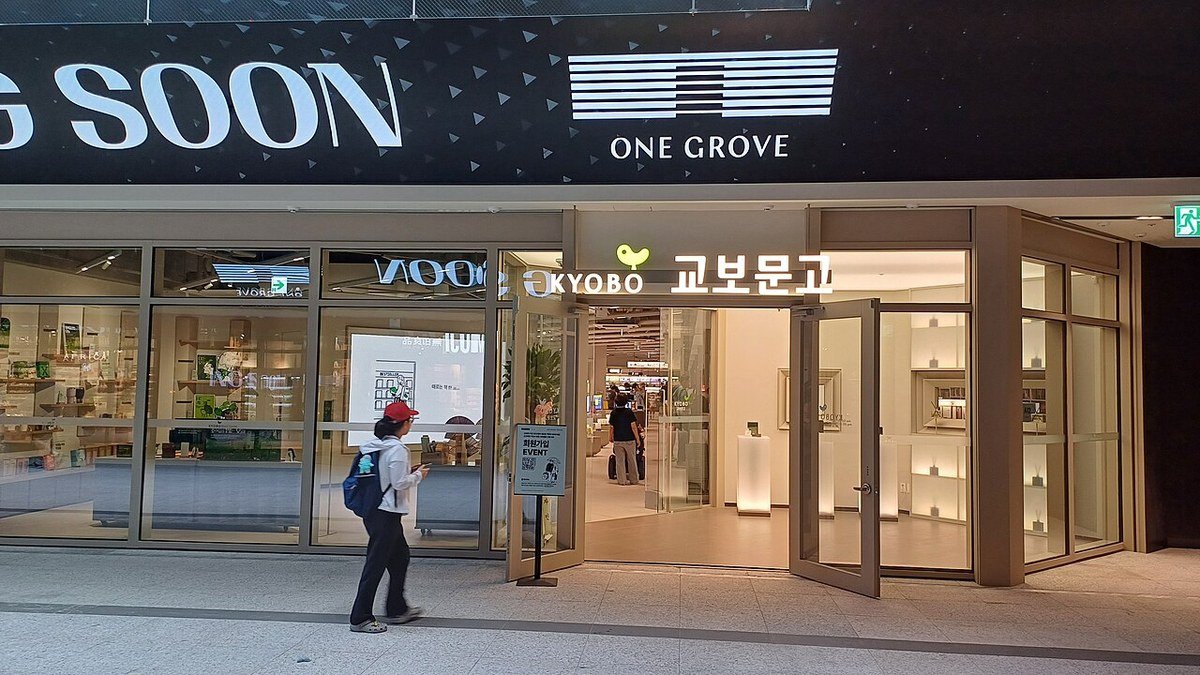 밤에 불이 켜진 교보문고 원그로브점 유리문 입구와 그 앞을 지나는 사람
