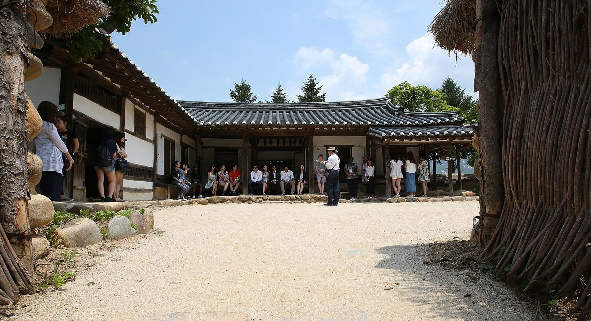 짚 담장 너머 한옥 처마 아래 모인 관람객