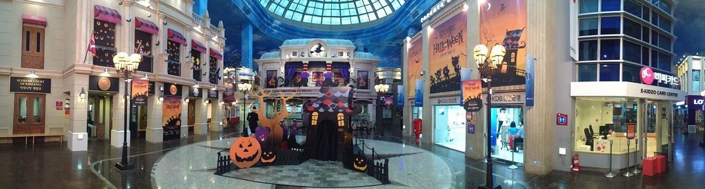 Wide hall under a glass dome with a Korean supreme-court sign and Halloween banners