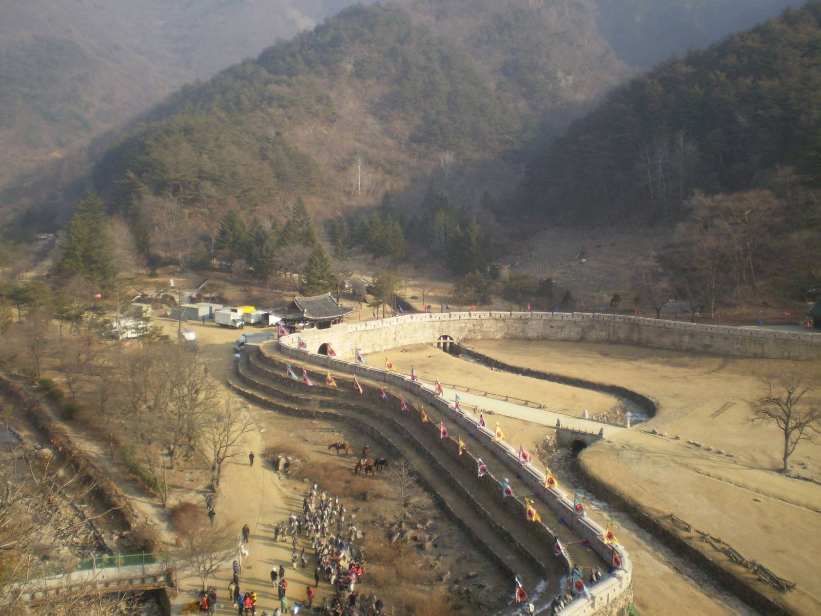 First gate Juheulgwan at Mungyeong Saejae, with stone walls, flags, and the gatehouse