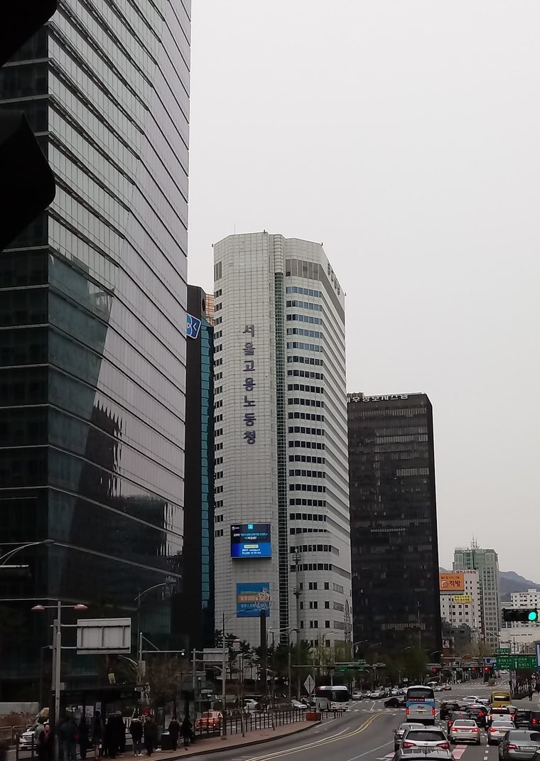 서울 도심 도로변에 선 서울고용노동청 고층 건물과 앞 도로의 차량들